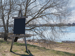 Old wooden sign stand by a river, Sunny day, copy space.