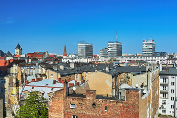 A panorama of the city of Poznań with modern skyscrapers and a tower of a Gothic church.