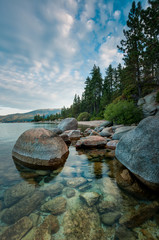 Portrait view of rocky shore with trees and clouds at Lake Tahoe California