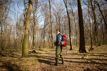 Young man with backpack hiking in the forest. Nature and physical exercise concept