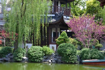 Authentic Japanese house on the bank of a pond surrounded by trees and stones. Beautiful summer landscape.
