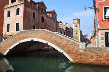 Fototapeta na wymiar Canal and bridge in quieter area of Venice with wall and tower of the Arsenale .