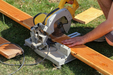 A worker saw wood with a chop saw