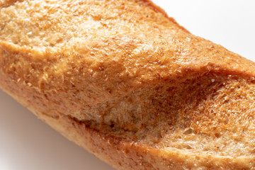 Wheat baked bread with golden crust on white background close up, bakery and grocery concept
