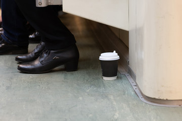 Disposable Cup of coffee is on the floor in the subway train