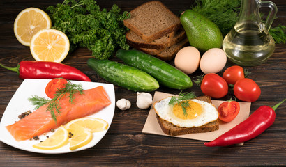 .red fish with lemon and vegetables on wooden background