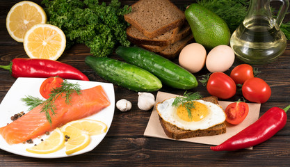 .red fish with lemon and vegetables on wooden background