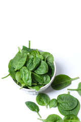 Fresh spinach leaves in white bowl on white isolated background. The concept of healthy eating and vegetarianism