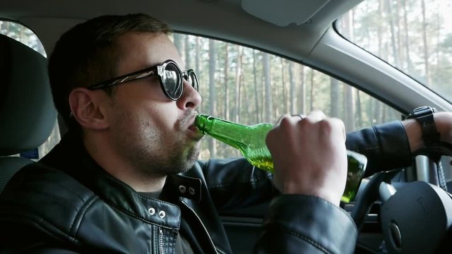 Close-up of Drunk driver drinking beer while driving, traffic offense