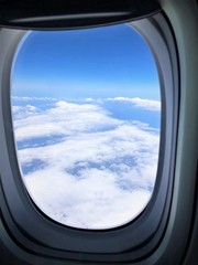 Blue sky with white clouds as looking through airplane window on the flight from South Korea to Atlanta Georgia USA .