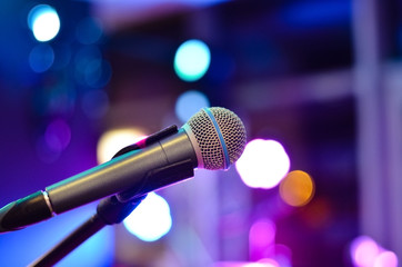 Obraz premium Close-up of microphone on a defocused background with multi colored lights at a concert .