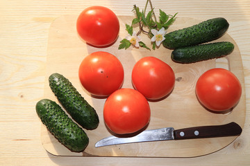 Tomatoes and cucumbers on a light wooden background, tasty and healthy food, diet food, harvesting in the village