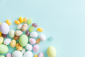 Happy Easter concept. Preparation for holiday. Easter candy chocolate eggs and jellybean sweets isolated on trendy pastel blue background. Simple minimalism flat lay top view copy space