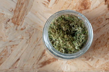 a glass jar filled with marijuana tops, medical sativa cannabis with low CBD content