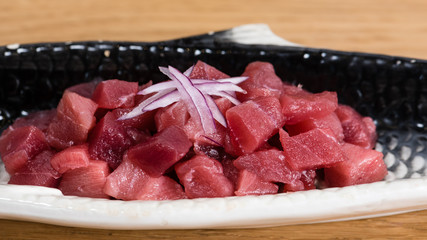 bluefin tuna tartare with chopped red onion, served on a fish-shaped plate