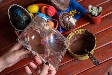 Chocolate derretido vertido en un molde, en el fondo huevos de Pascua y confites