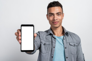 Focus on the smartphone with white screen which a man holding  in his hand. Mockup