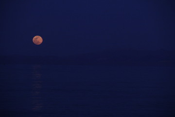 full moon over the sea against the backdrop of the mountains
