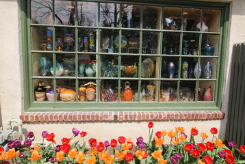 The flower garden is in front of the store's window.