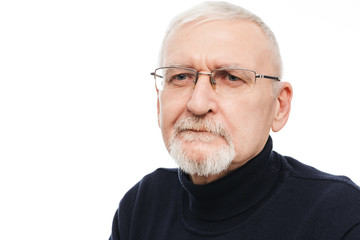 Portrait of old handsome man with gray hair and beard in eyeglasses and black sweater thoughtfully looking aside over white background isolated