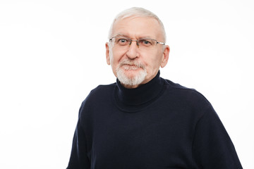 Portrait of old man with gray hair and beard in eyeglasses and black sweater amazedly looking in camera over white background isolated