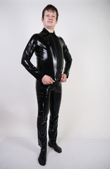 Caucasian nerd chubby man dressed in fashionable latex rubber fetish clothes on white background in Studio