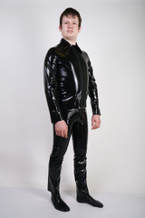 Caucasian nerd chubby man dressed in fashionable latex rubber fetish clothes on white background in Studio