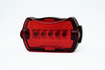 Rear bike lamp lighting in red color with a slight reflection isolated on white background. Bicycle mounting black plastic. Front view.