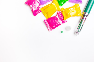Diabetes green pen with colorful hard candies isolated on white background.