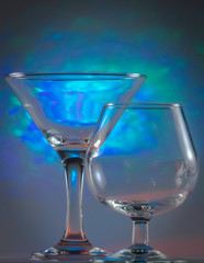 Martini Glass together with Cognac Glass with flashing bright blue lights on background