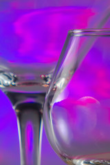 Martini Glass together with Cognac Glass with flashing bright magenta lights on background