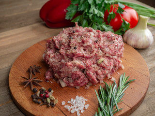 Minced beef with onions and black pepper on a wooden board 