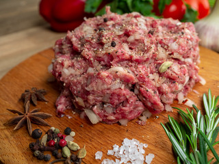 Minced beef with onions and black pepper on a wooden board 