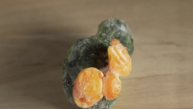 Frozen vegetables rotates on a wooden board; carrots and broccoli.