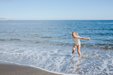 Blonde girl plays happy on the beach