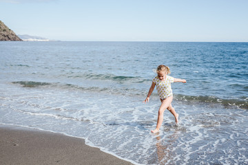 Fototapeta na wymiar Blonde girl plays happy on the beach