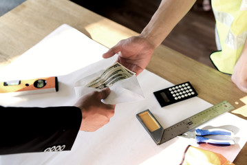 Top view of owner or boss hand giving money to employee or hired person for his wage or salary over table. The payment is in paper envelope. Business concept.