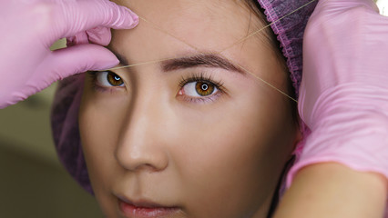 Microbleeding and eyebrow architecture. Beautician forms lines of symmetry on girl's face. Cosmetic...