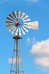 Windmill and Sky - A retro metal windmill stands tall against a cloudy blue sky in Indiana.