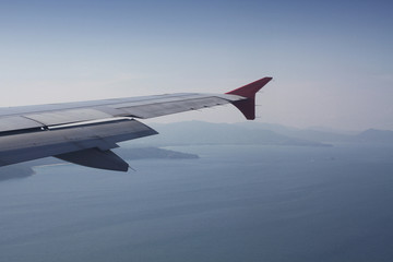 flying and traveling abroad, bird eye view from airplane window on the jet wing on wonderful island beach in vacation summer, journey backgrounds