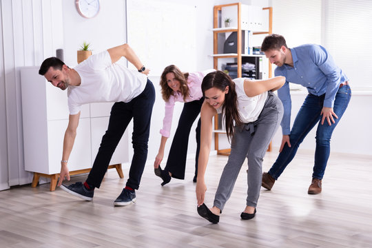 Businesspeople Doing Stretching Exercise At Workplace