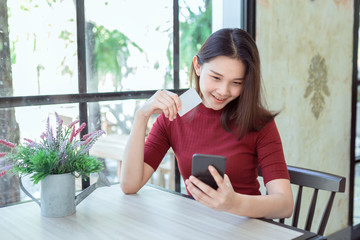 Young woman holding credit card and using smart phone