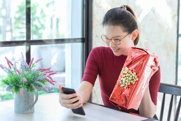 Young woman holding gift box and video call