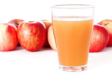 Glass of Apple Juice with Red Apples Behind Glass Isolated