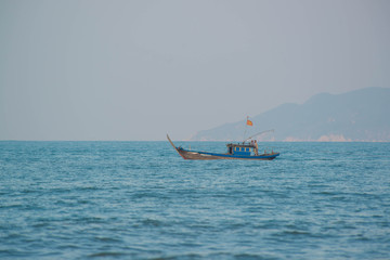 Naklejka na ściany i meble A beach in Hoi An with tourists, boats and fisherman, Vietnam.