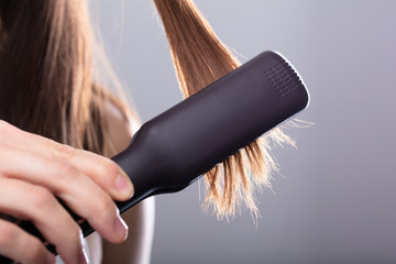 Woman Straightening Hair With Straightener