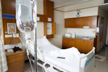 View of hand hang on Intravenous Fluid with patient bed backgroud.