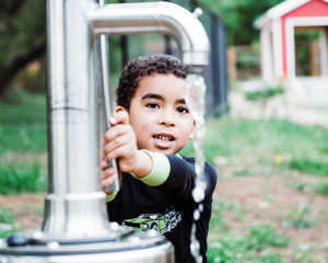 Boy drinking water from water pump