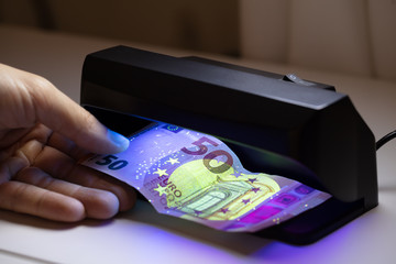 Person Checking Banknote Through The Currency Detector