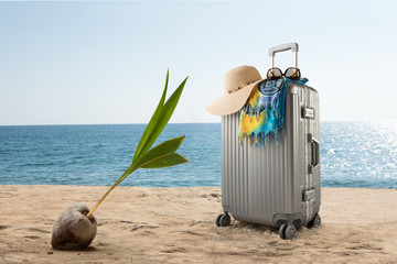 view of  suitcase with hat, pareo and sunglasses on sunny tropic beach